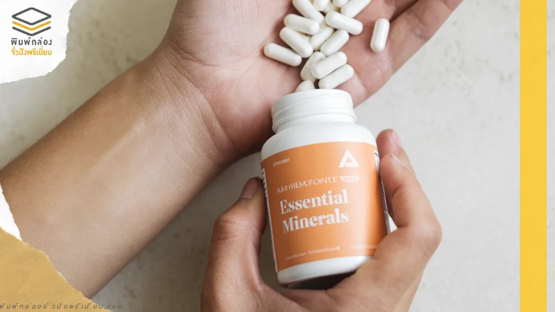อาหารเสริมมีฉลากสินค้า Essential Minerals ในขวดสีขาวและส้ม พร้อมแคปซูลสีขาวในมือ แสดงถึงประโยชน์ในการดูแลสุขภาพ